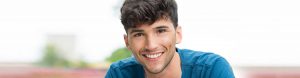 young teenage boy smiling wearing blue